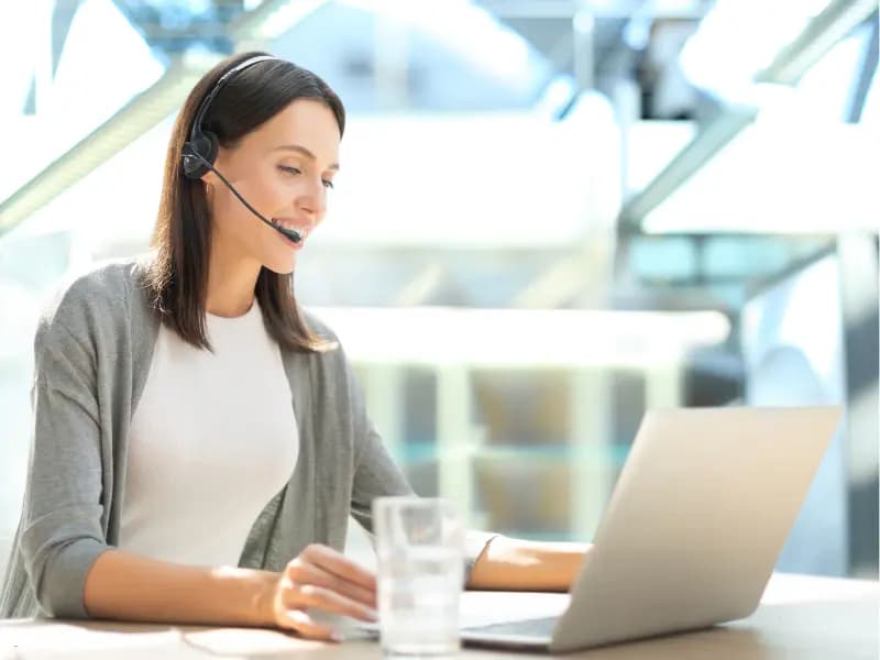 Online scheduling platforms accessed by a woman wearing a headset while working on her laptop