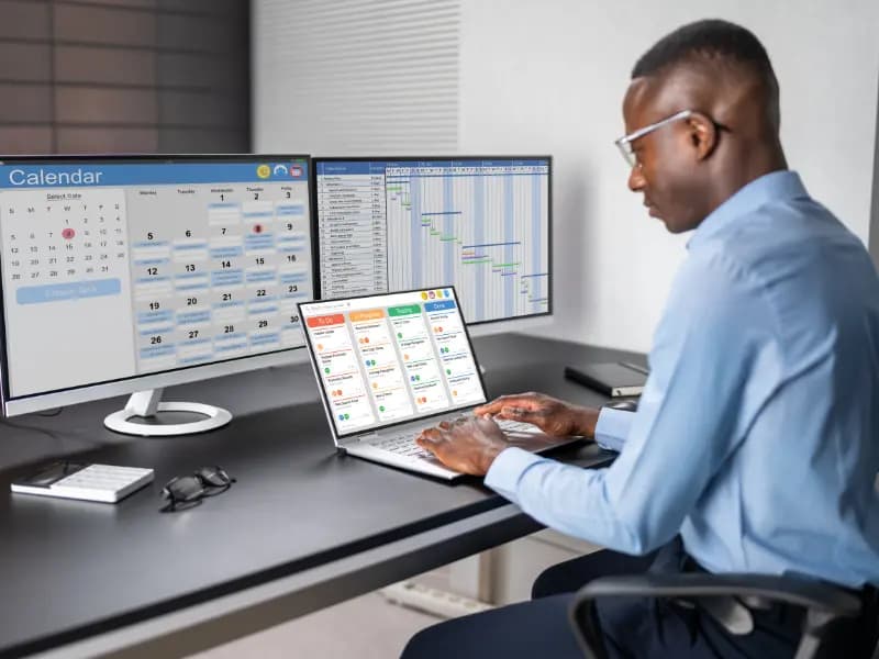 Scheduling software for appointments displayed on multiple screens as a professional manages tasks on a laptop